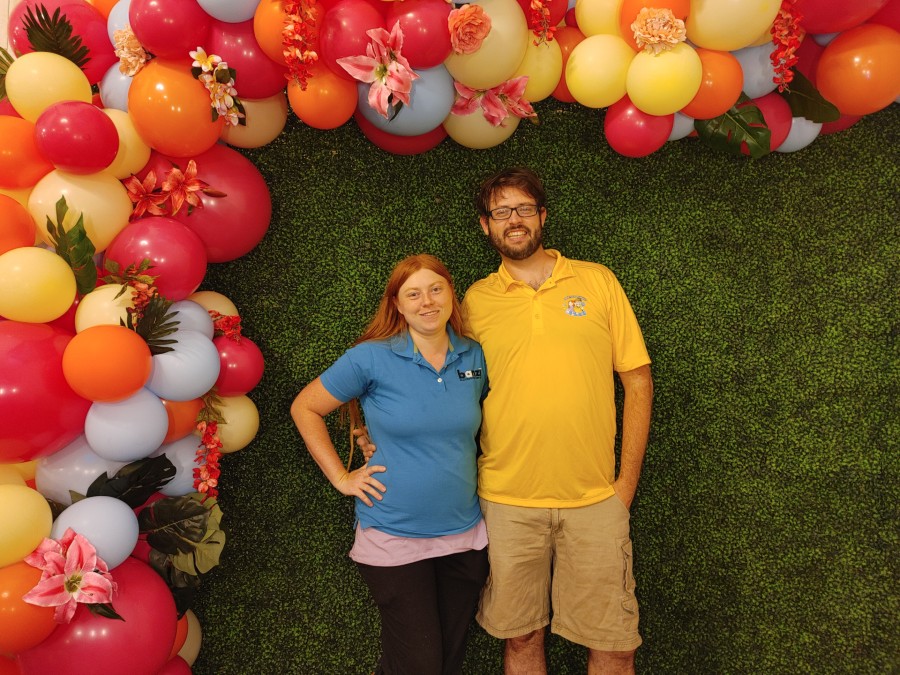two people standing with a balloon arch above them
